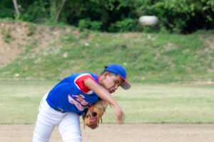 A kid in a blue uniform playing baseball