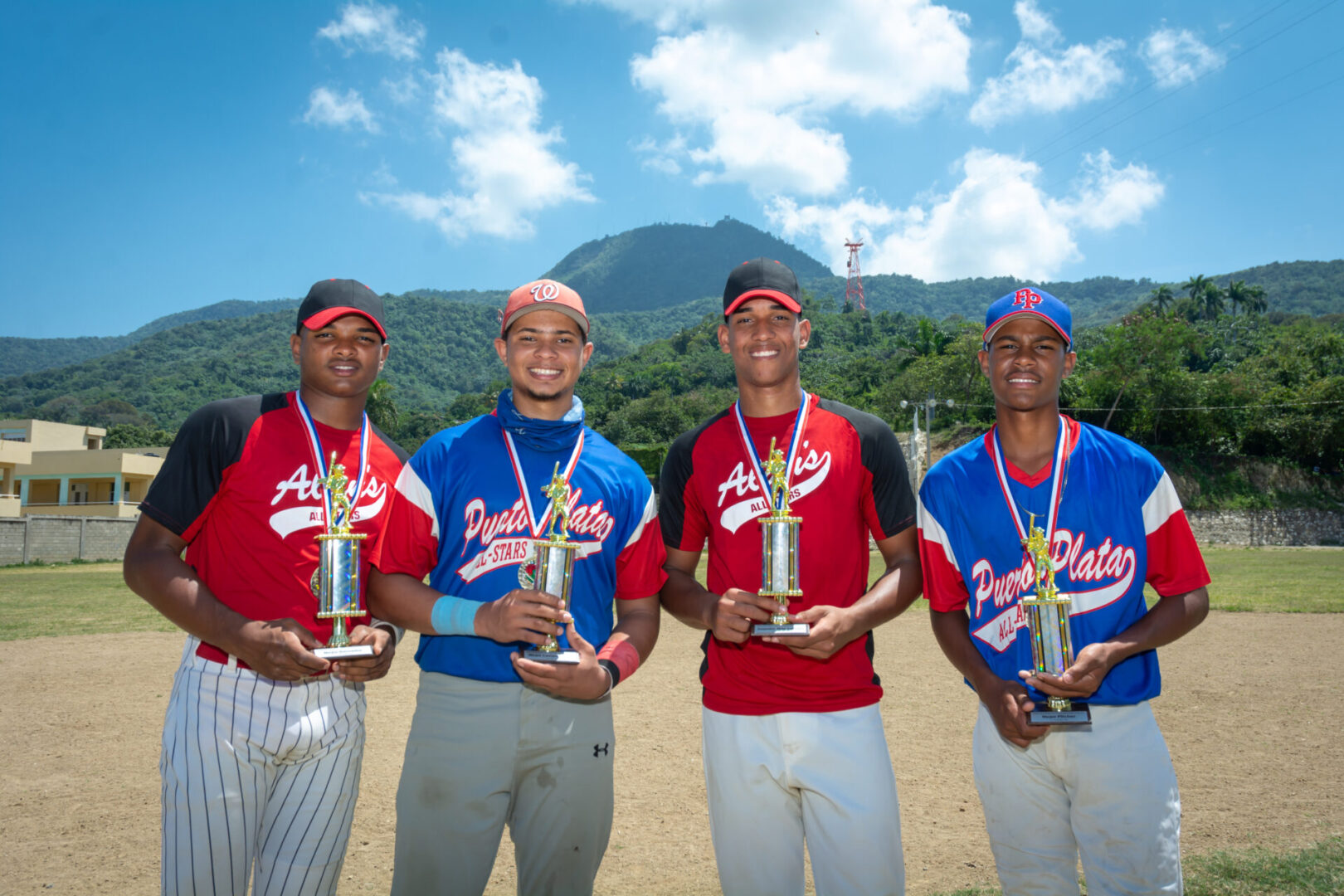 four baseball players each holding trophies and wearing medals